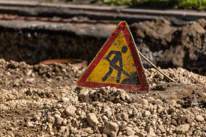 a dirty roadworks sign standing on a pile of dirt