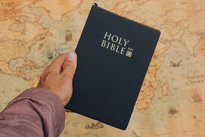 hand holding holy bible over world map