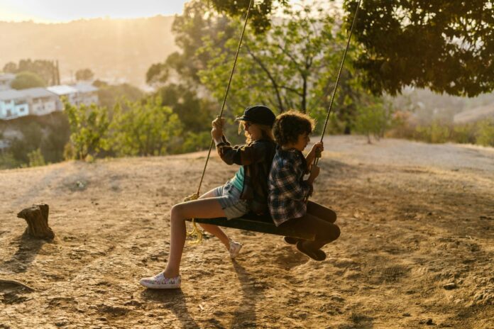 girl and boy in plaid shirts sitting on a swing